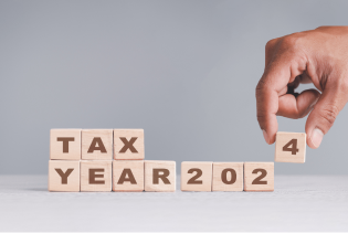 Hand placing wooden blocks that spells out Tax Year 2024